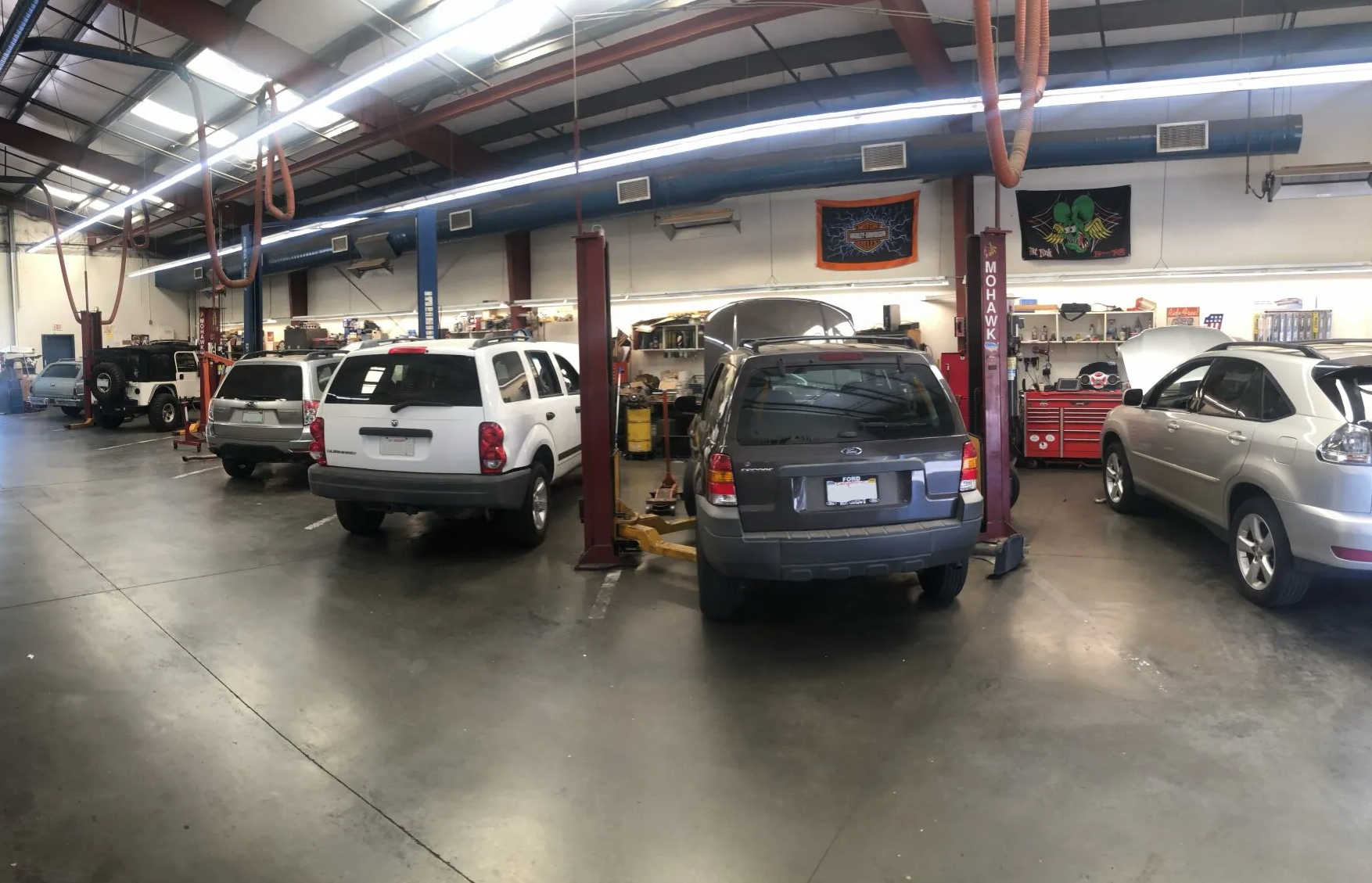Cars on lifts inside an auto repair shop. Several vehicles are being worked on in the garage.