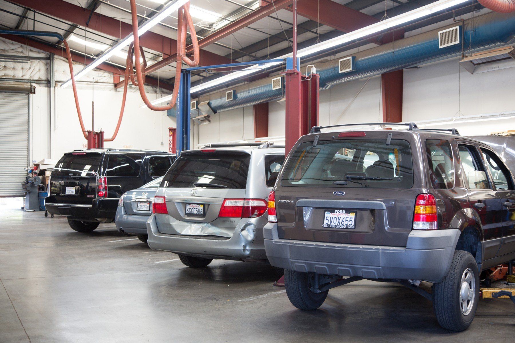 Cars in an auto repair shop: SUVs parked near lifts and repair equipment.