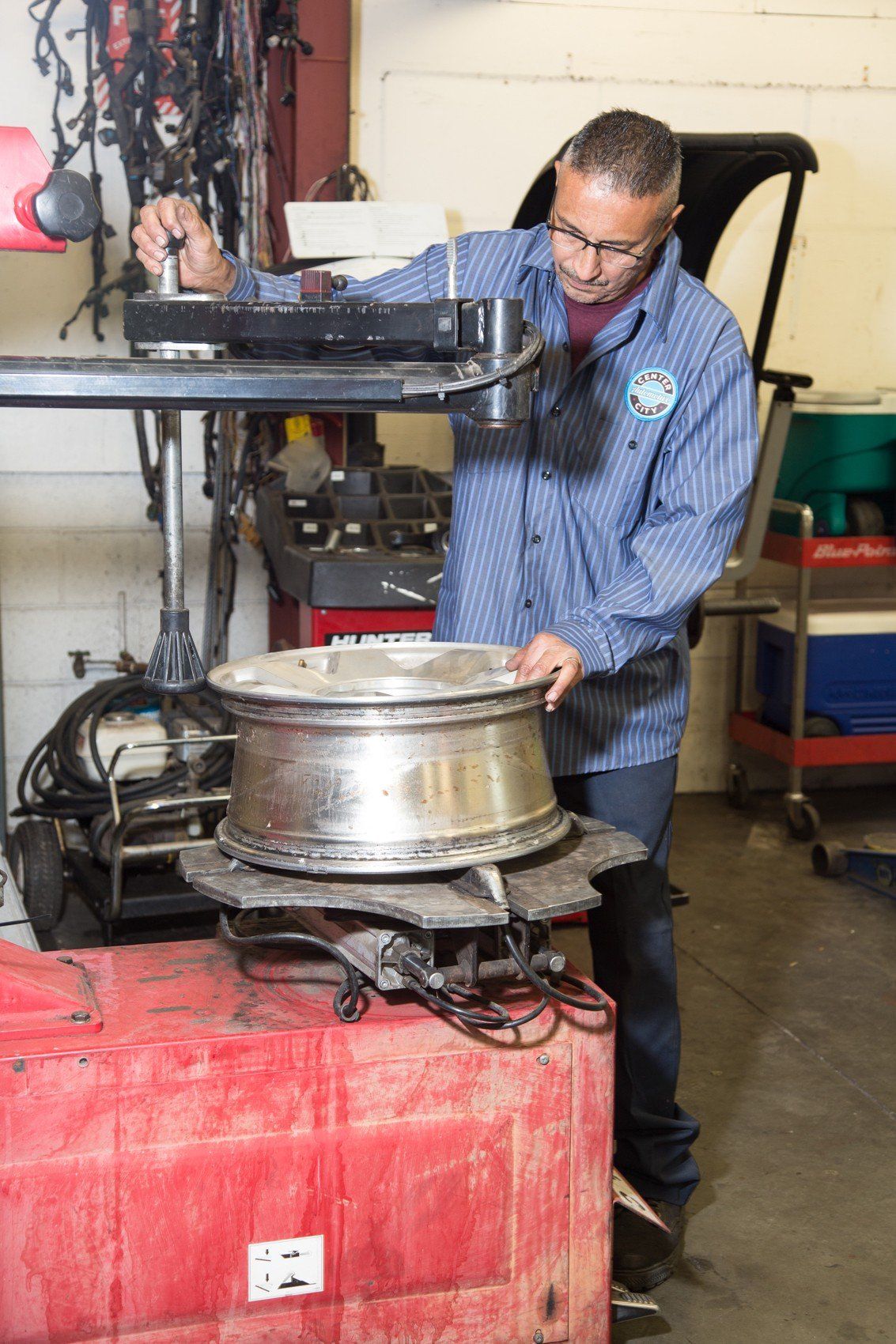 Mechanic working on a car wheel, using a tire machine in a shop.