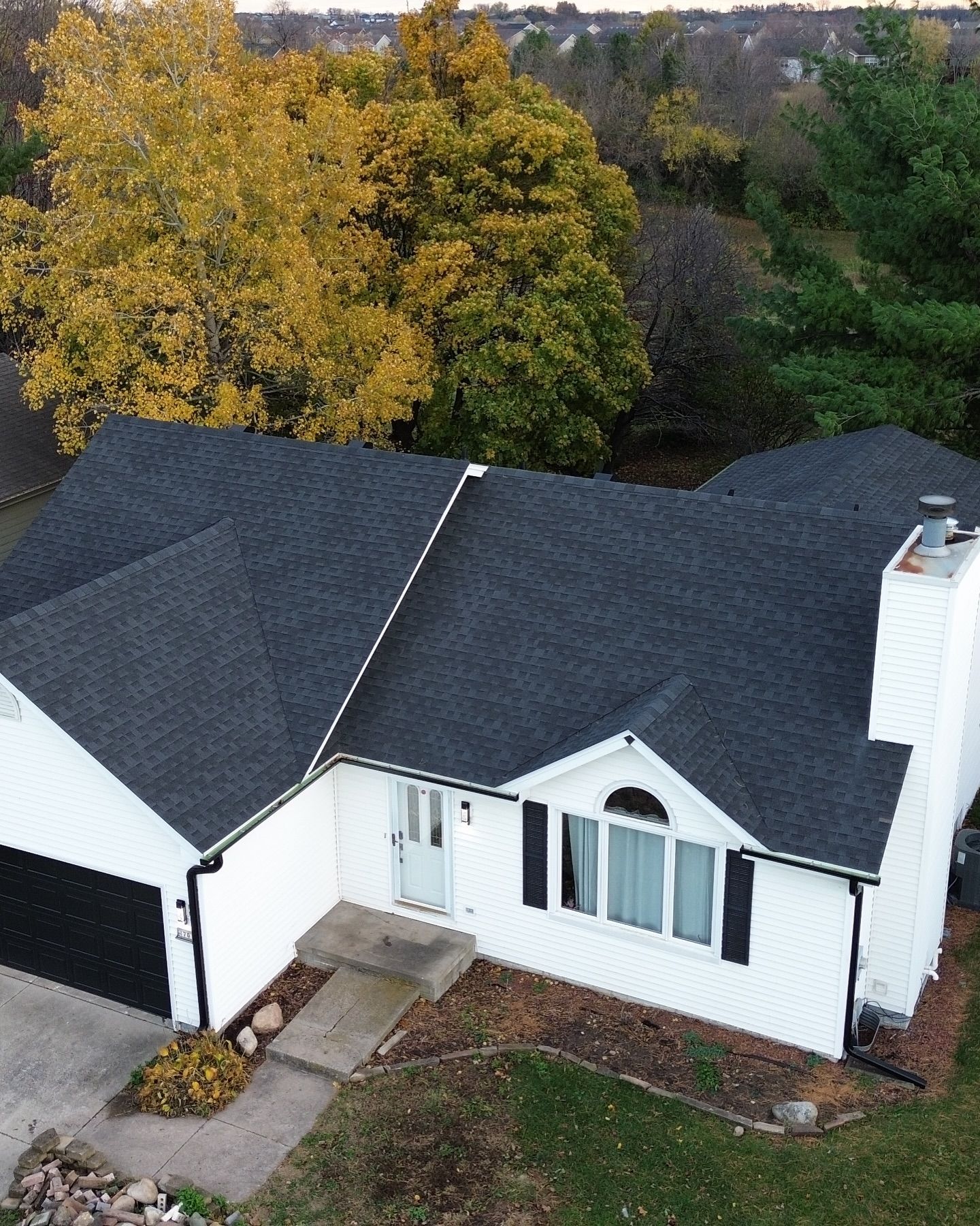 An aerial view of a white house with a black roof