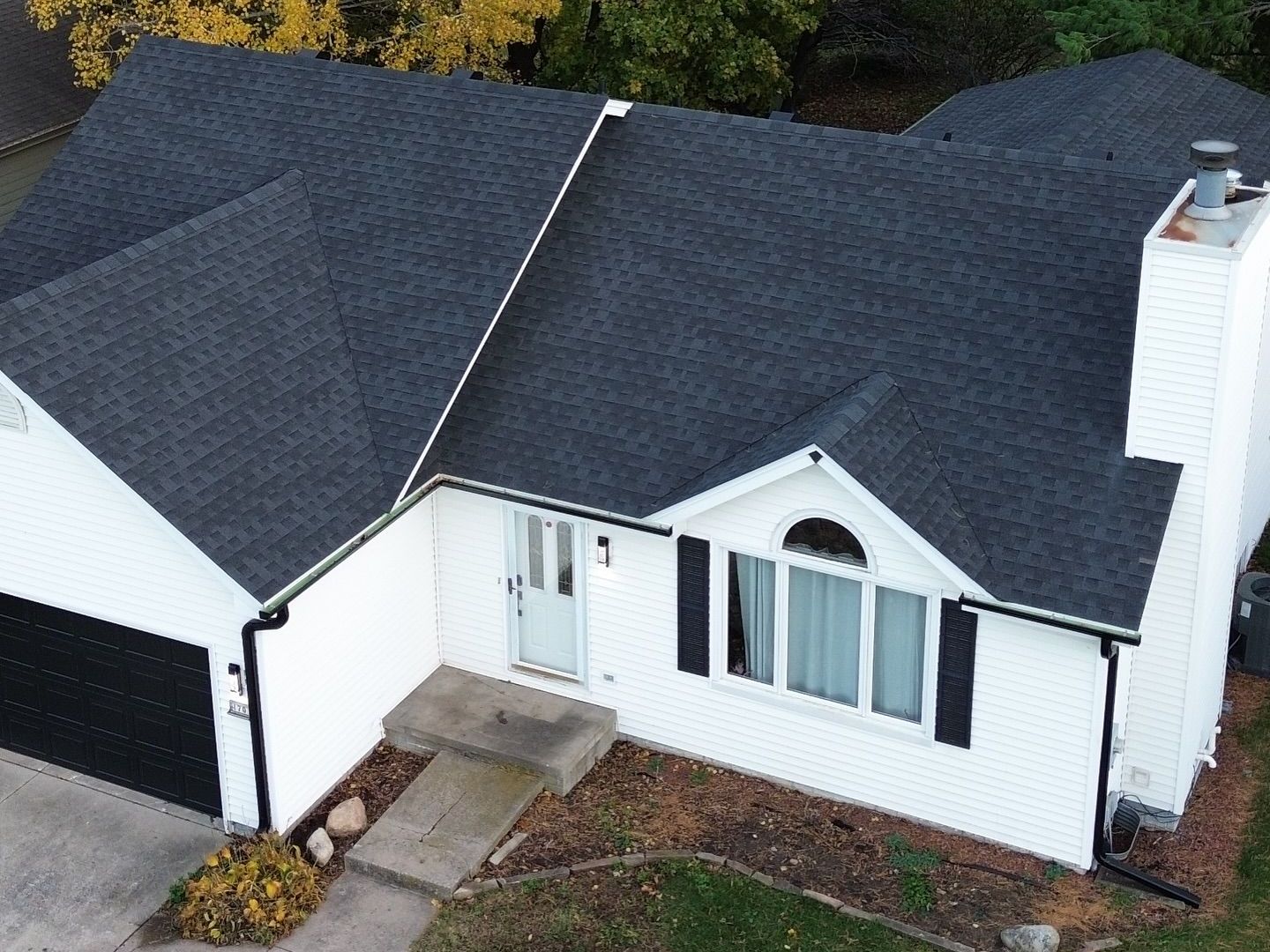 An aerial view of a white house with a black roof.