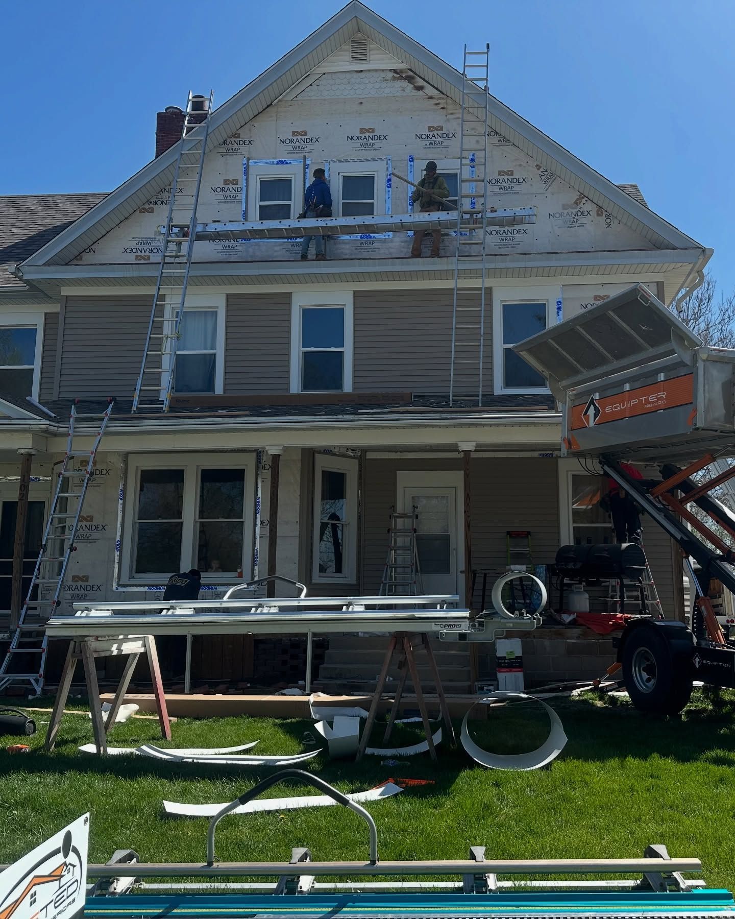 A house is being remodeled with scaffolding and a tractor.