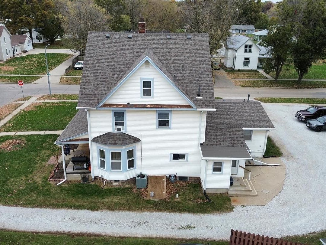 An aerial view of a white house with a gray roof.
