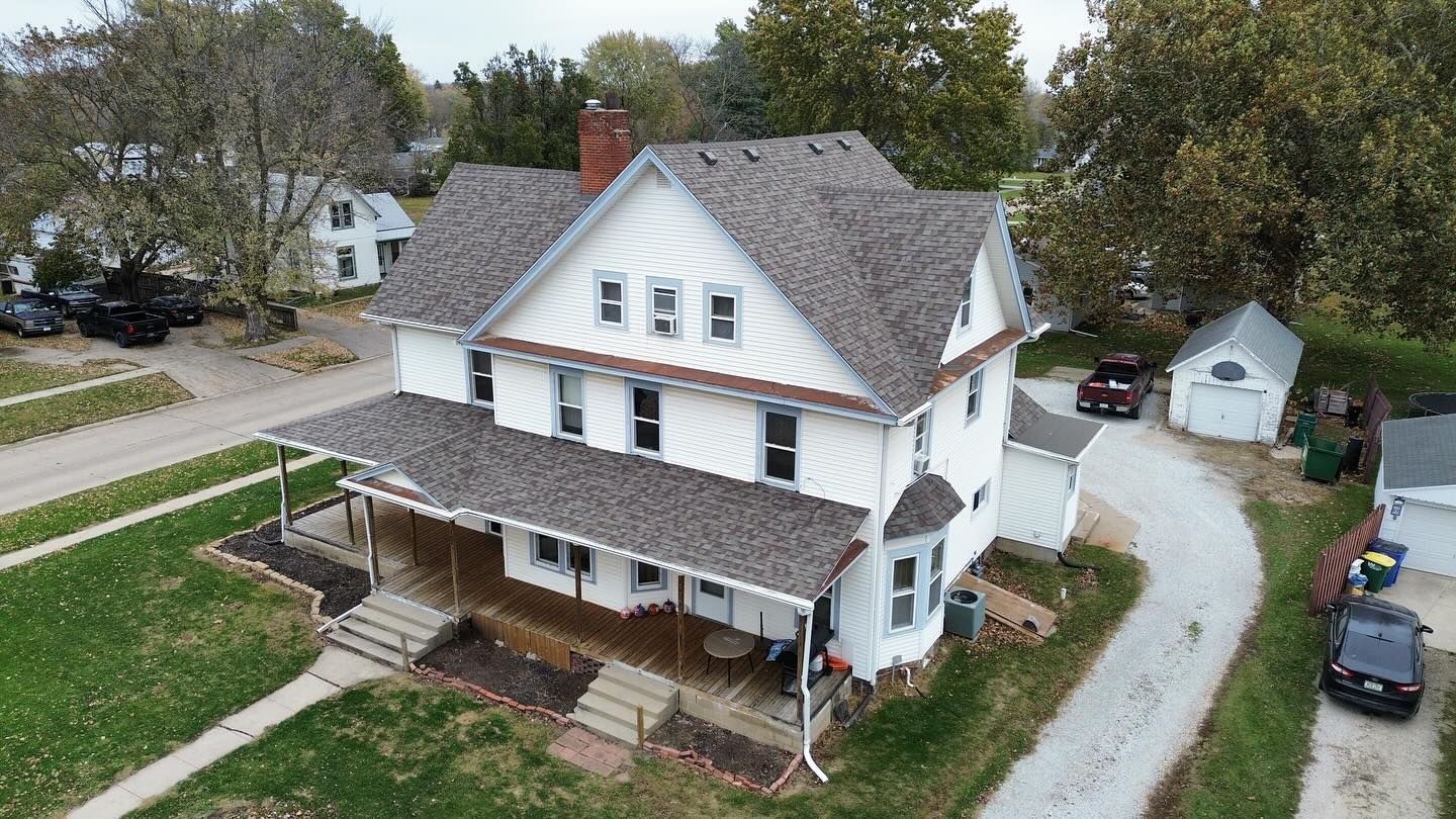 An aerial view of a large white house with a gray roof.