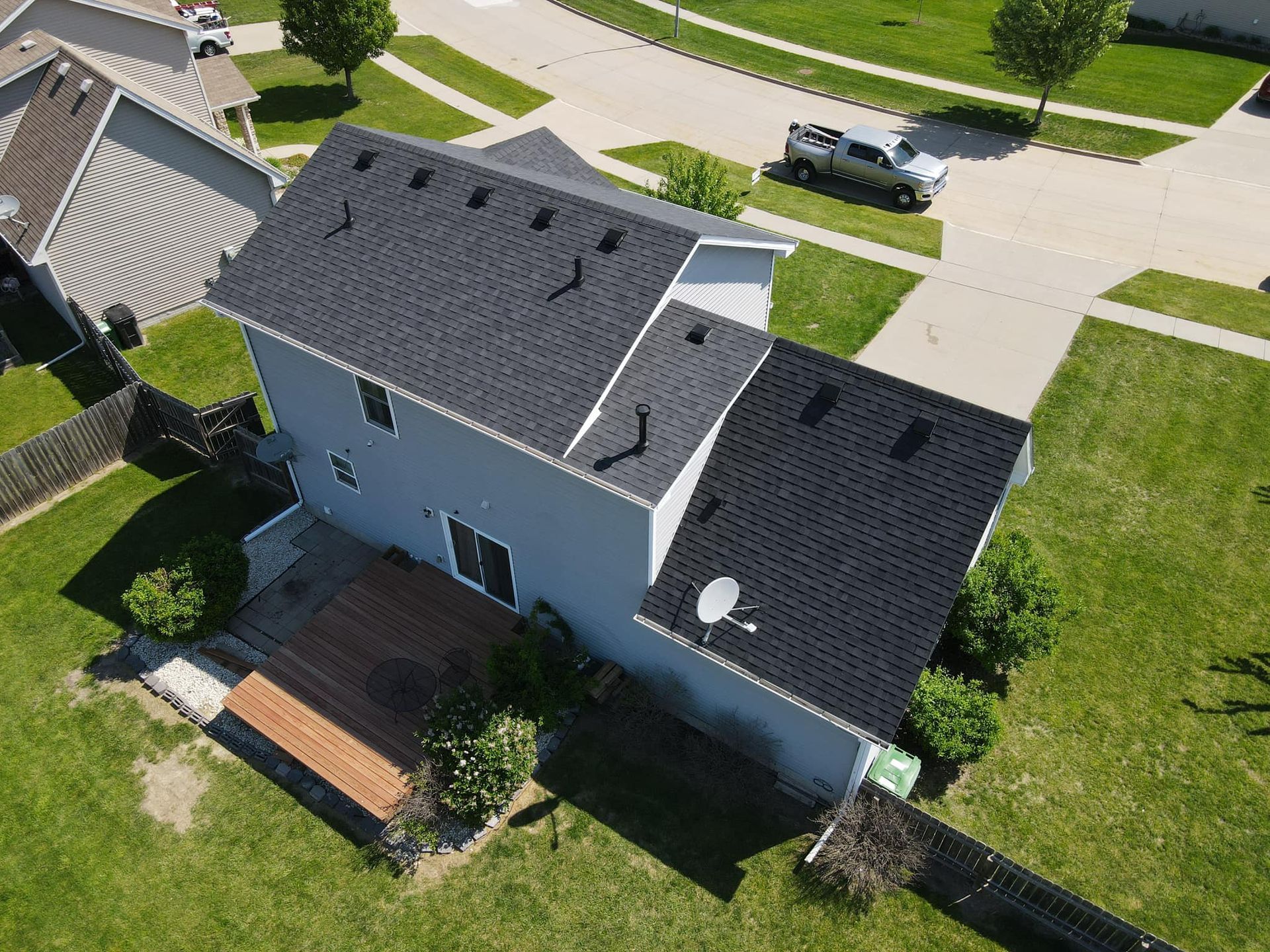 An aerial view of a house with a black roof in a residential area.