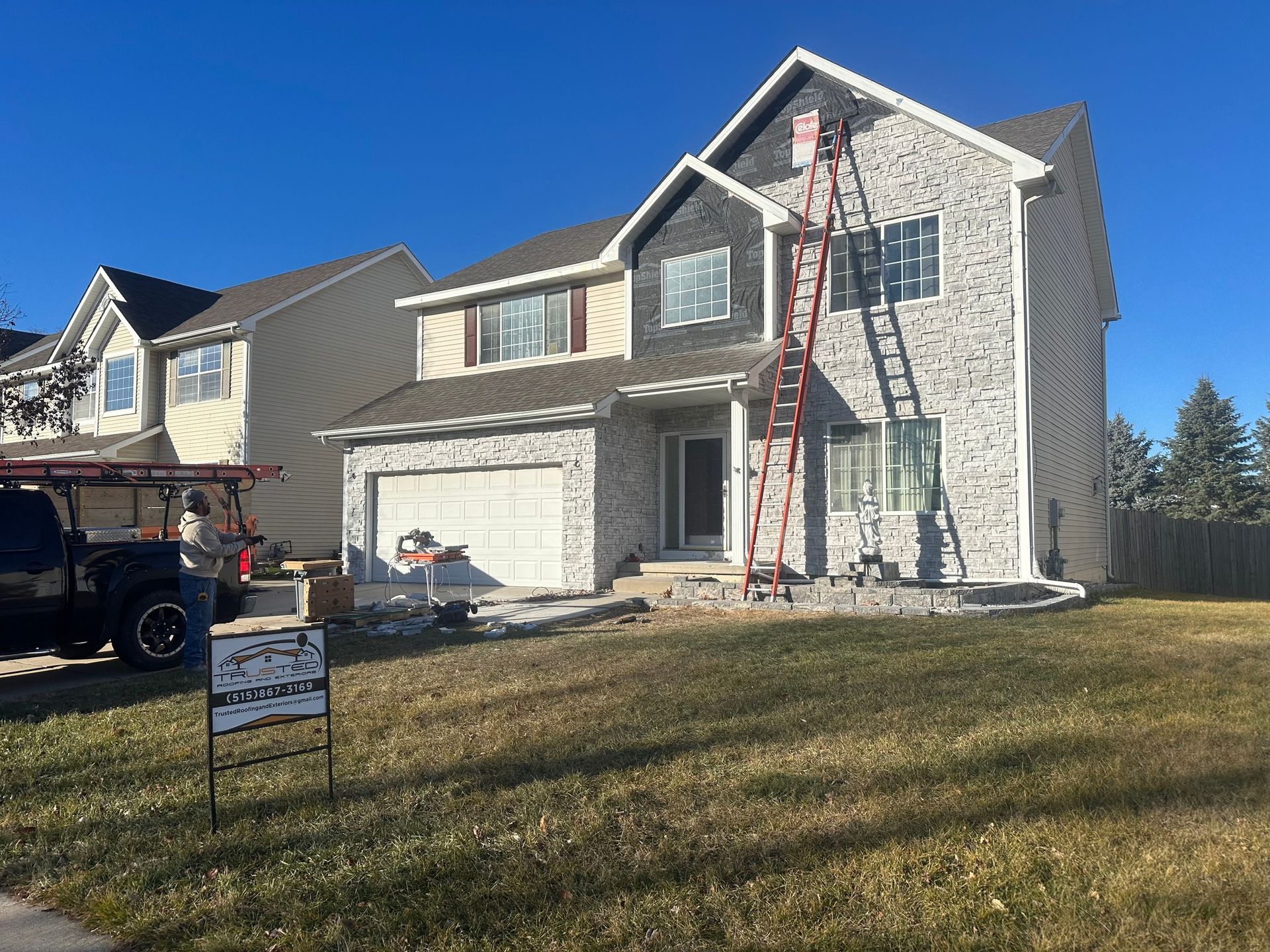 A large house with a ladder in front of it is being painted.