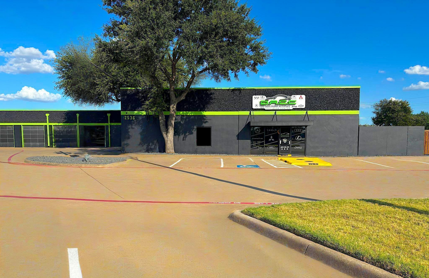 Exterior of a trampoline park with gray walls, a green stripe, and a tree.
