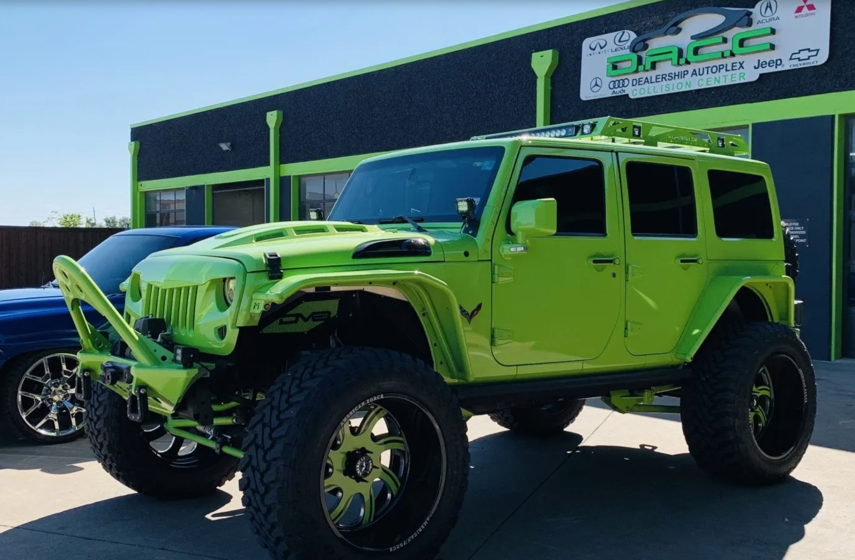 Bright green Jeep Wrangler with large tires parked in front of a business. The Jeep has a custom lift kit.