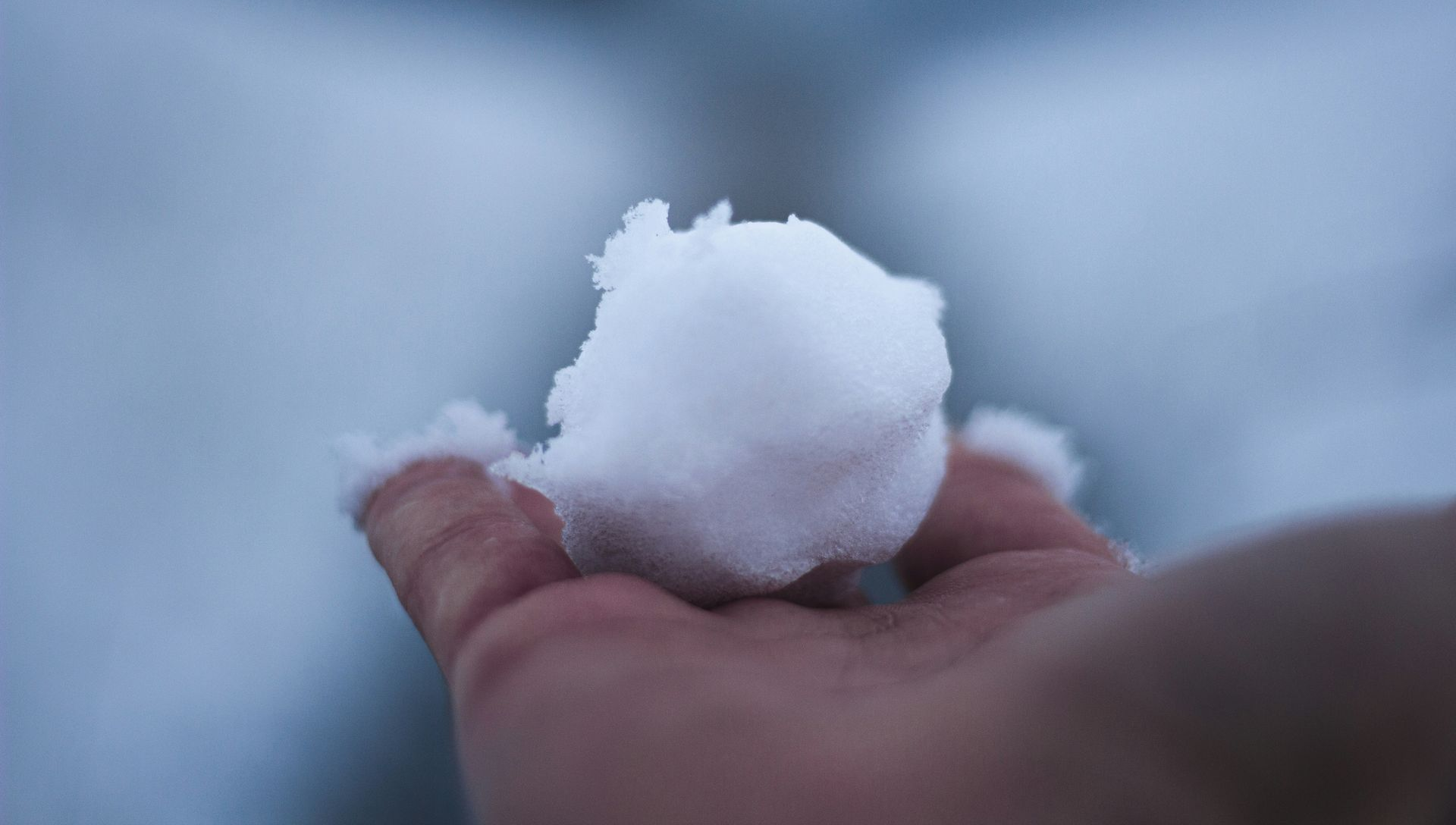 Hand holding a freshly made snowball, outside.