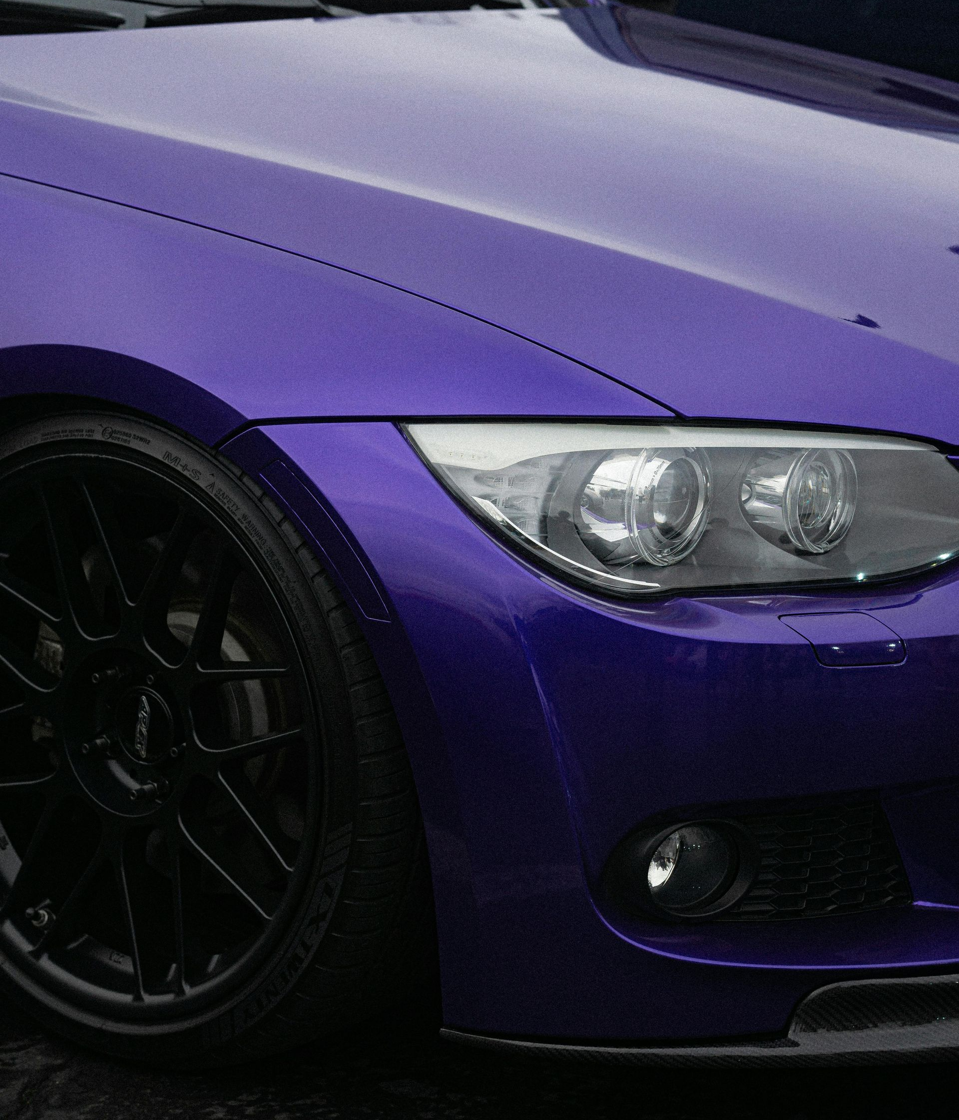 Purple BMW car with black wheels and headlights.