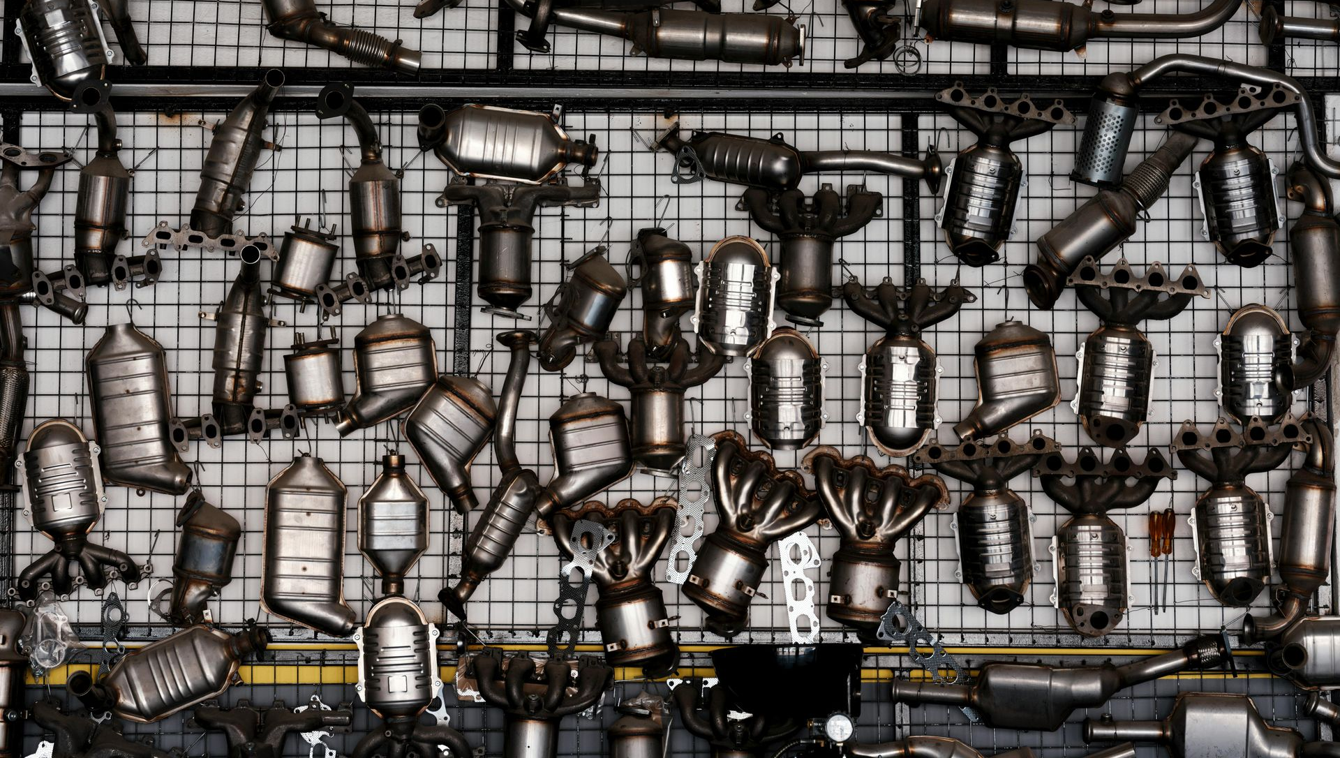 Scrap metal auto exhaust parts, tightly packed on a grid.