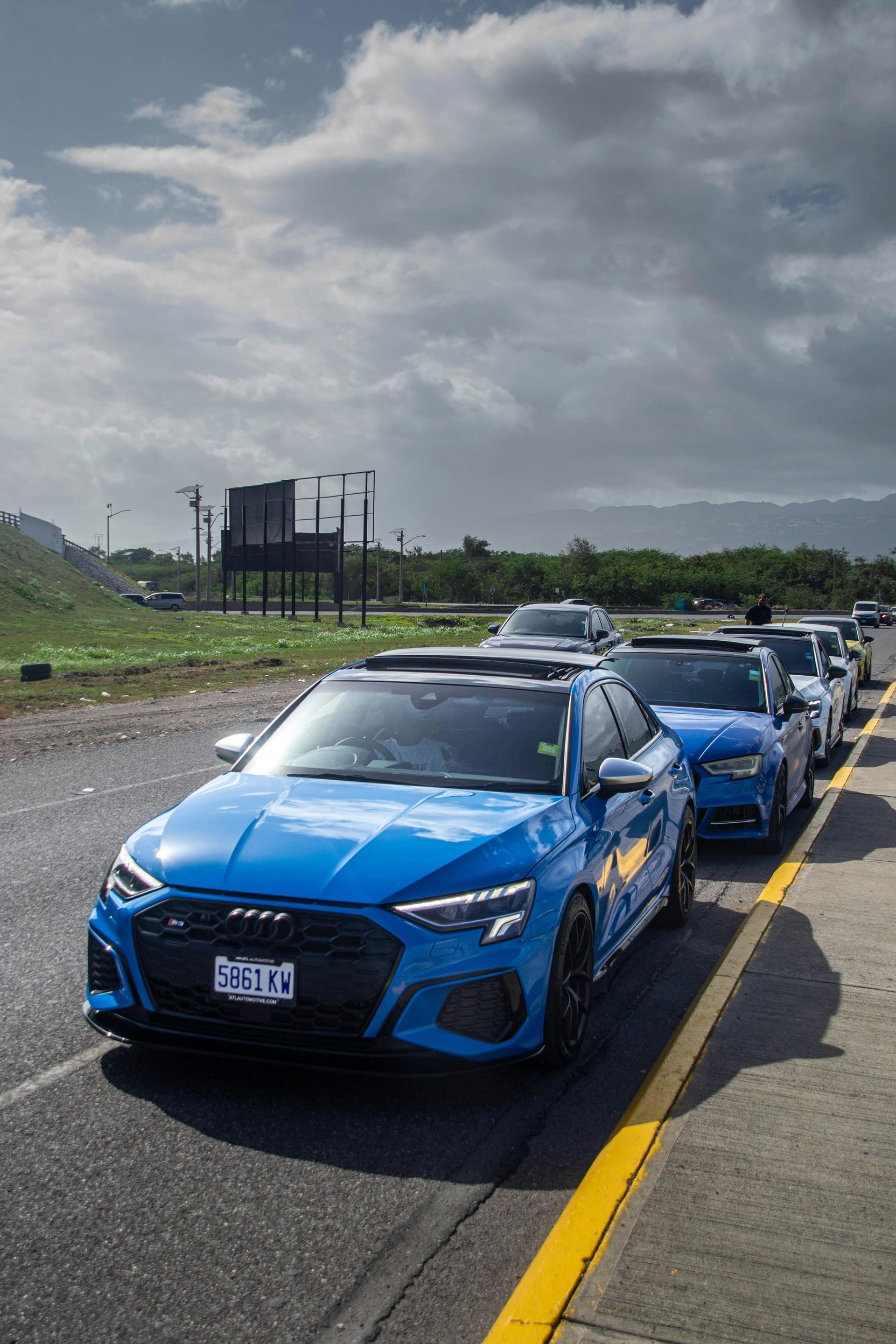 Man in overalls using a grinder on a red car in a garage, sparks flying.
