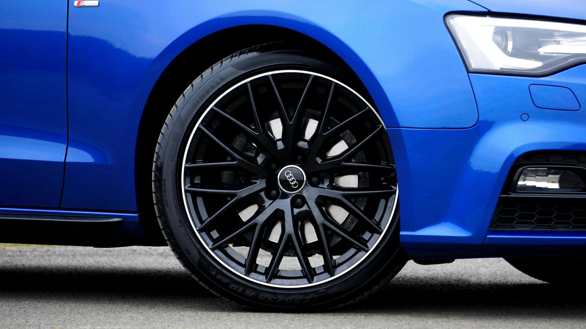 Blue car with a black rim and tire, white trim, against an asphalt background.