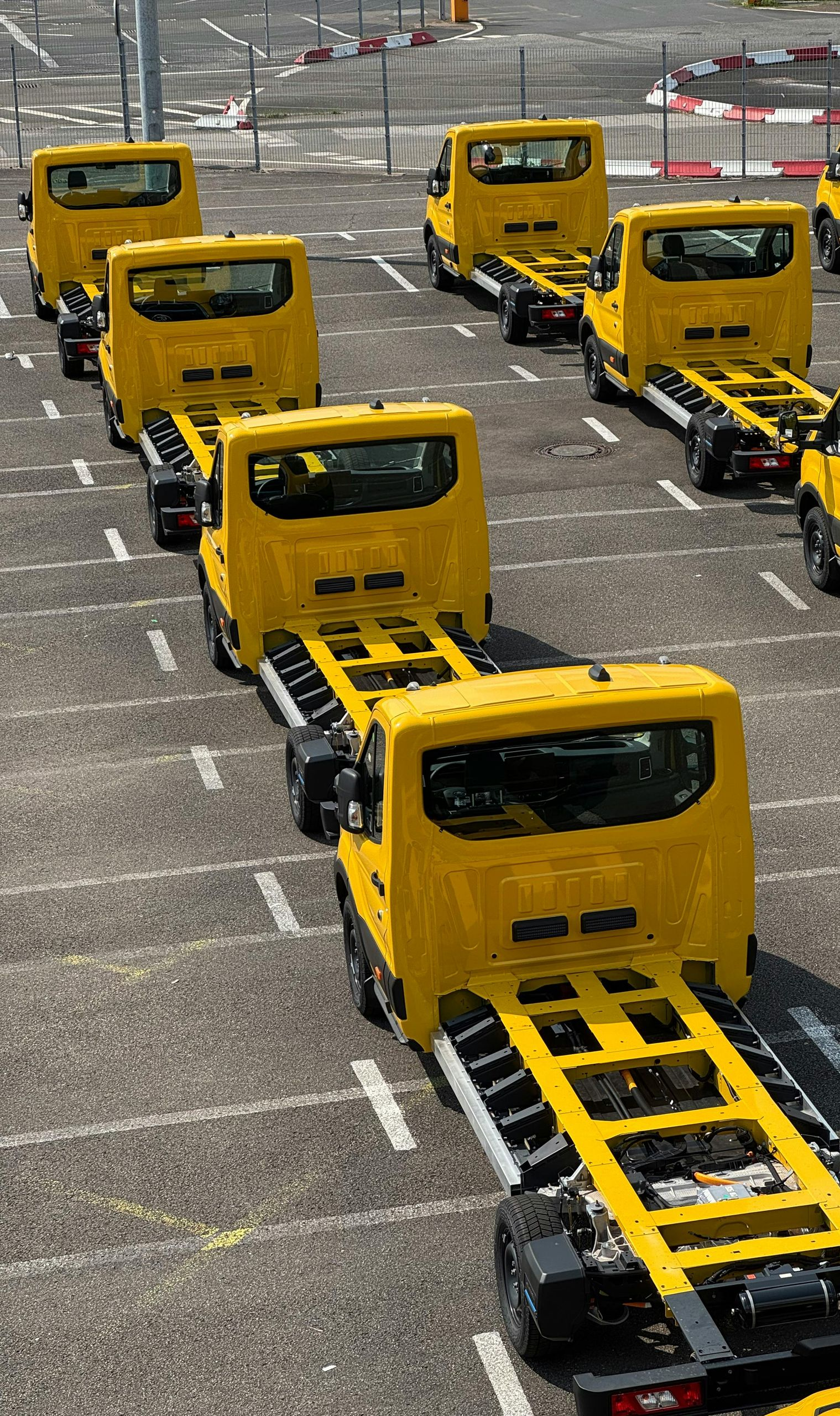 Yellow truck chassis parked in a lot, awaiting bodies.