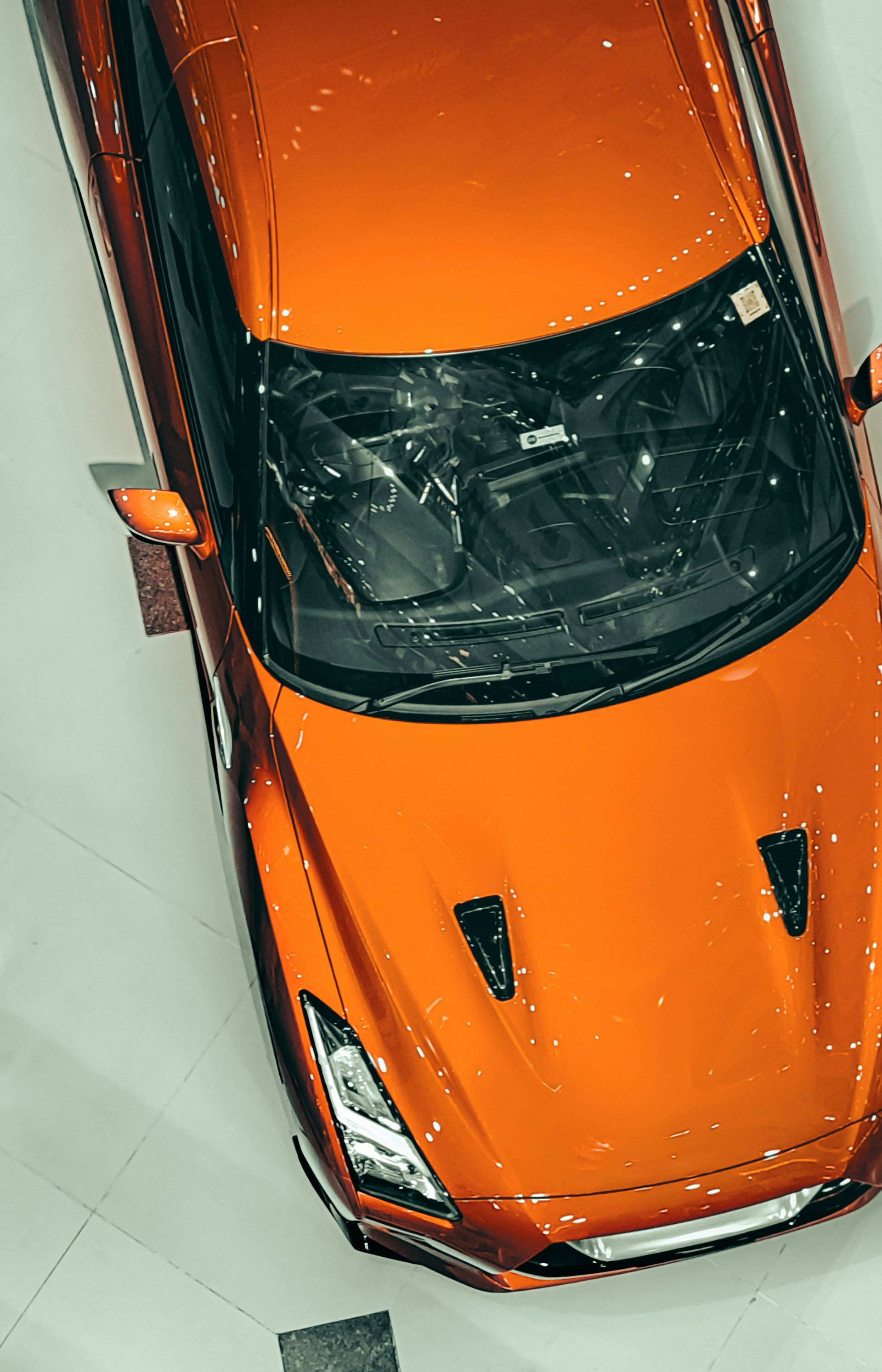 Orange sports car viewed from above in a showroom display