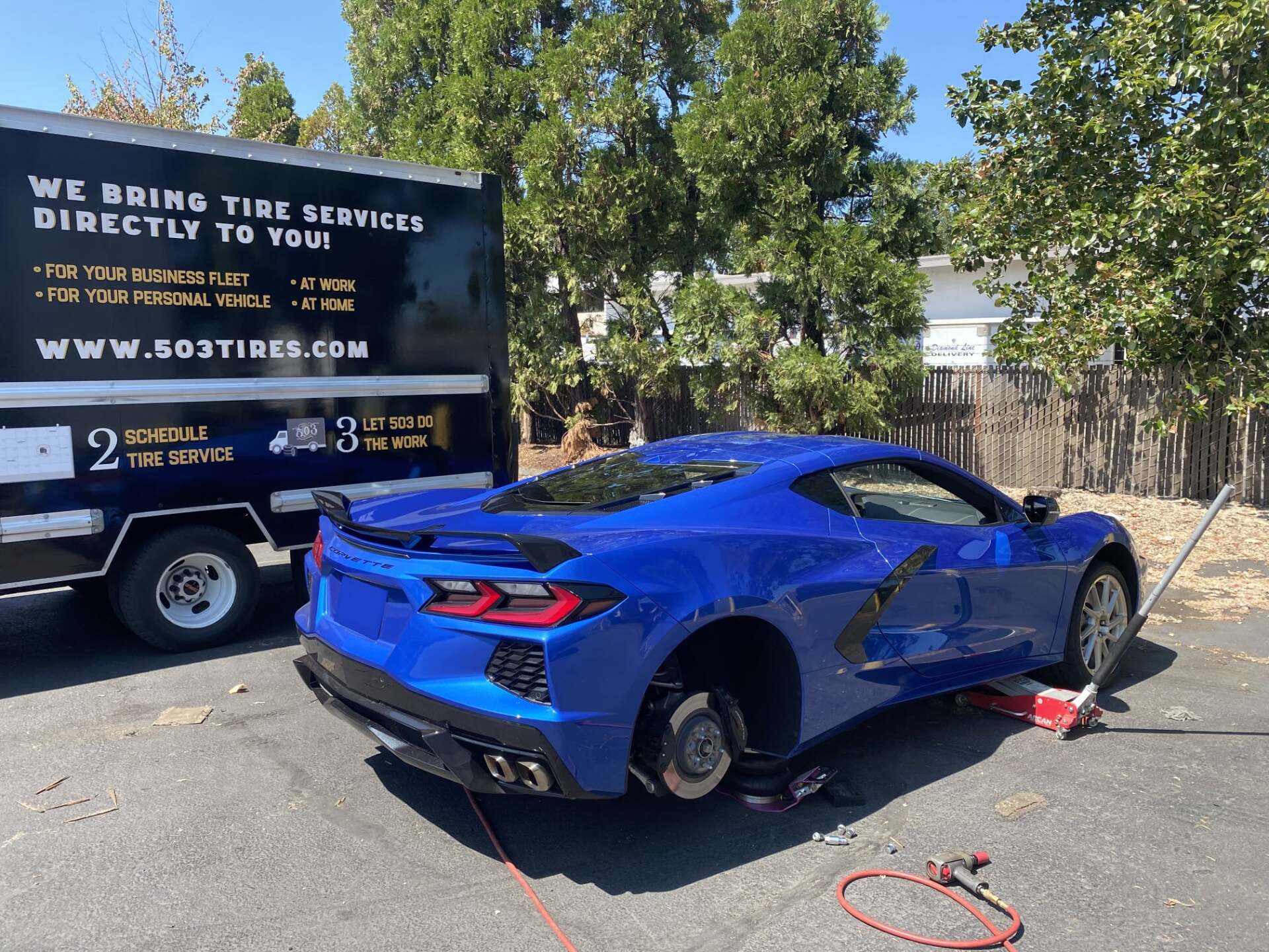 Blue sports car getting it's tires replaced.