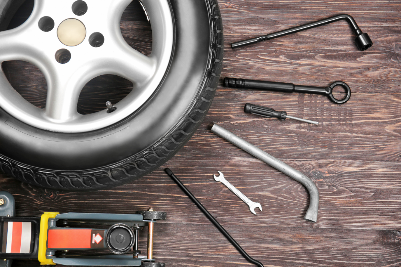 Car wheel with tools on wooden background