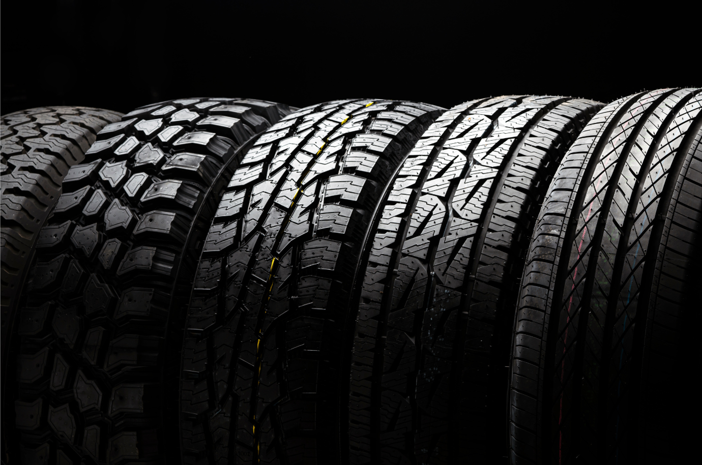 Five all-terrain tires on black background