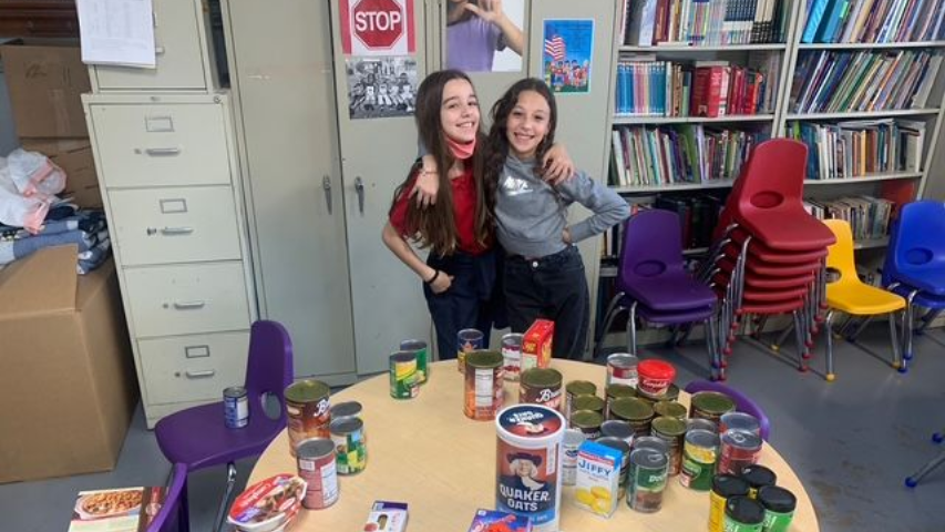 Woman reading a book with three children at a round table.