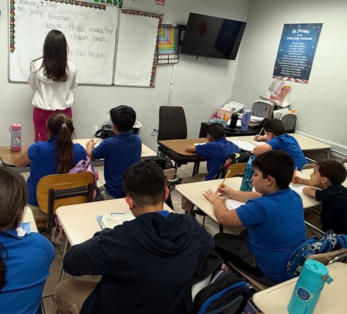 Woman reading a book with three children at a round table.