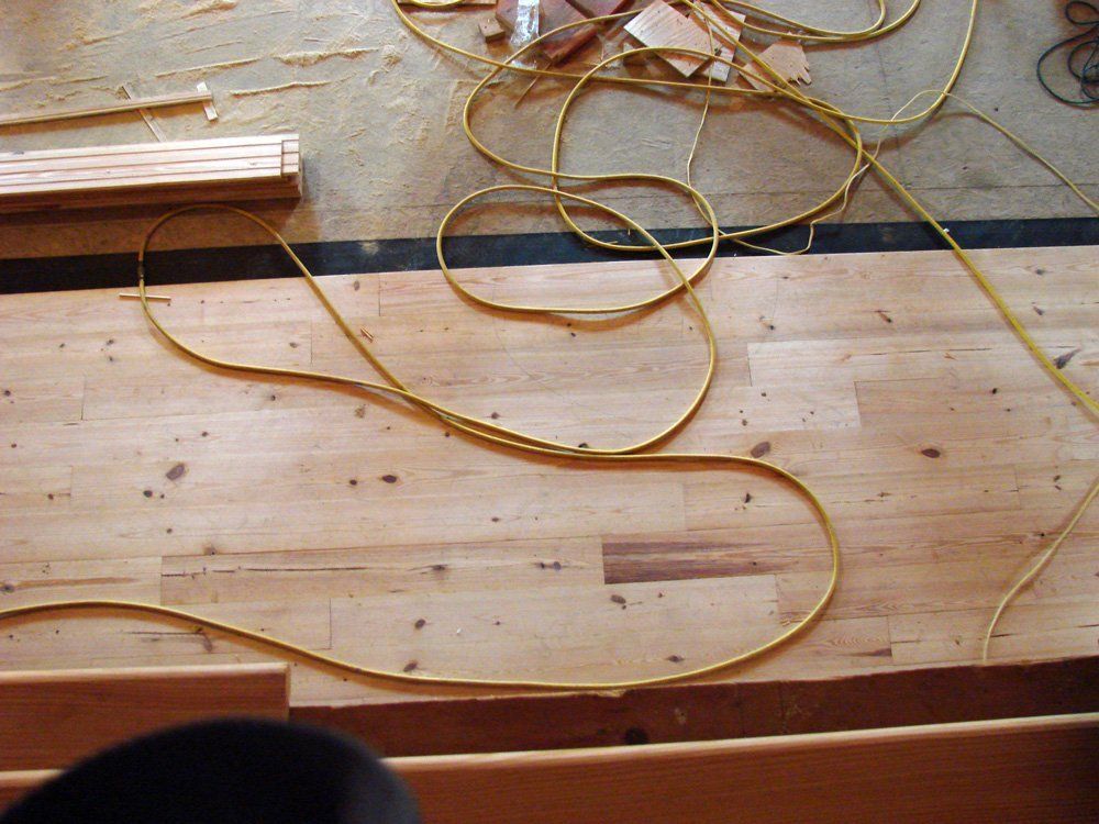 A bunch of wires are laying on a wooden floor.