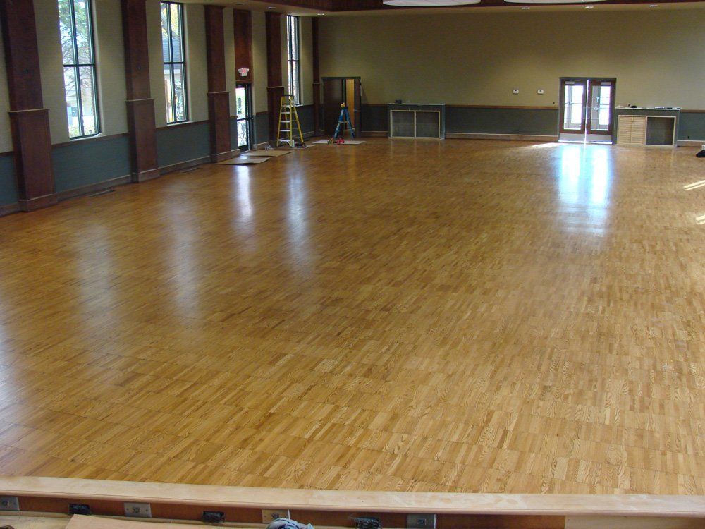 A large room with a wooden floor and a ladder.