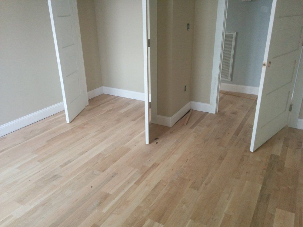 An empty room with hardwood floors and white doors.