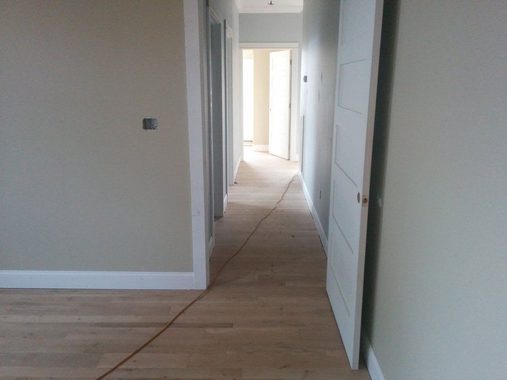 A long hallway with wooden floors and white walls.