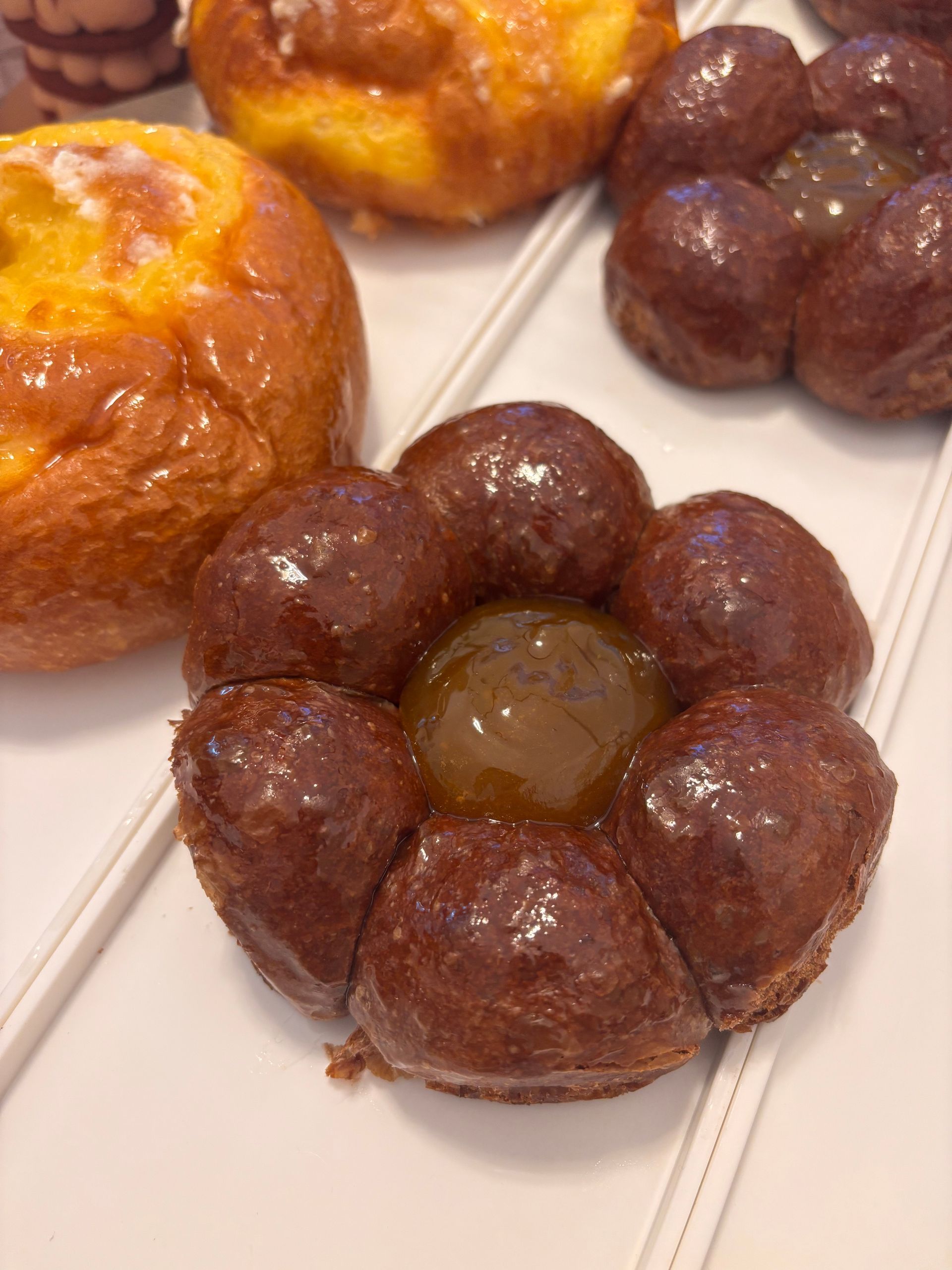 Muffin, caffè e zucchero su una tovaglia bianca, con un vaso di fiori, creano un'accogliente scena per la colazione.