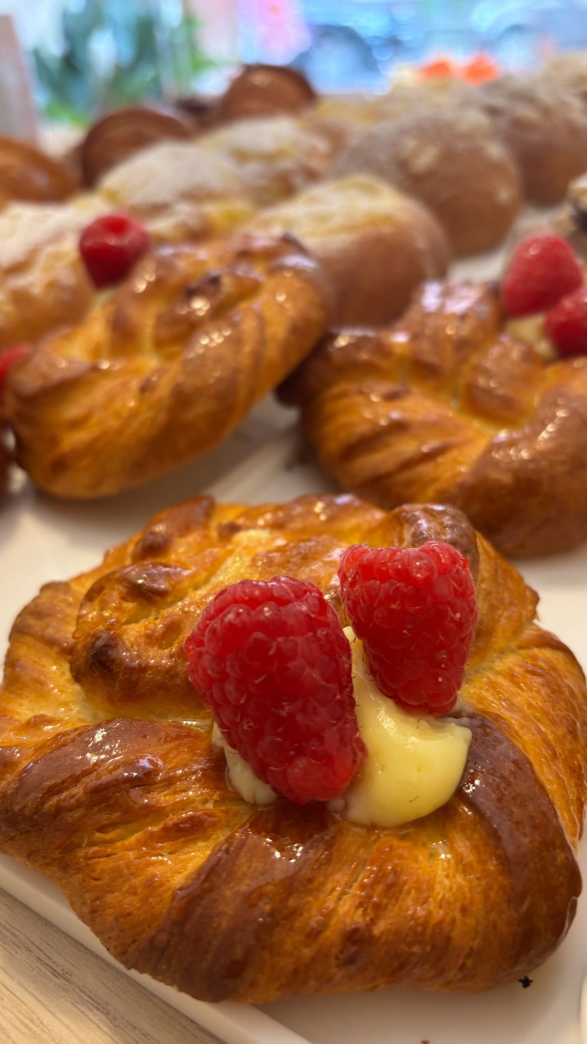 Caffè in una tazza decorata, limone, dolce e cucchiaino disposti su una tavola di legno.