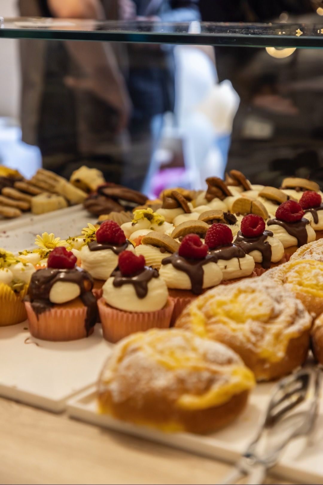 Vetrina di pasticceria in una panetteria con dessert assortiti e porte ad arco, un interno caldo e accogliente.