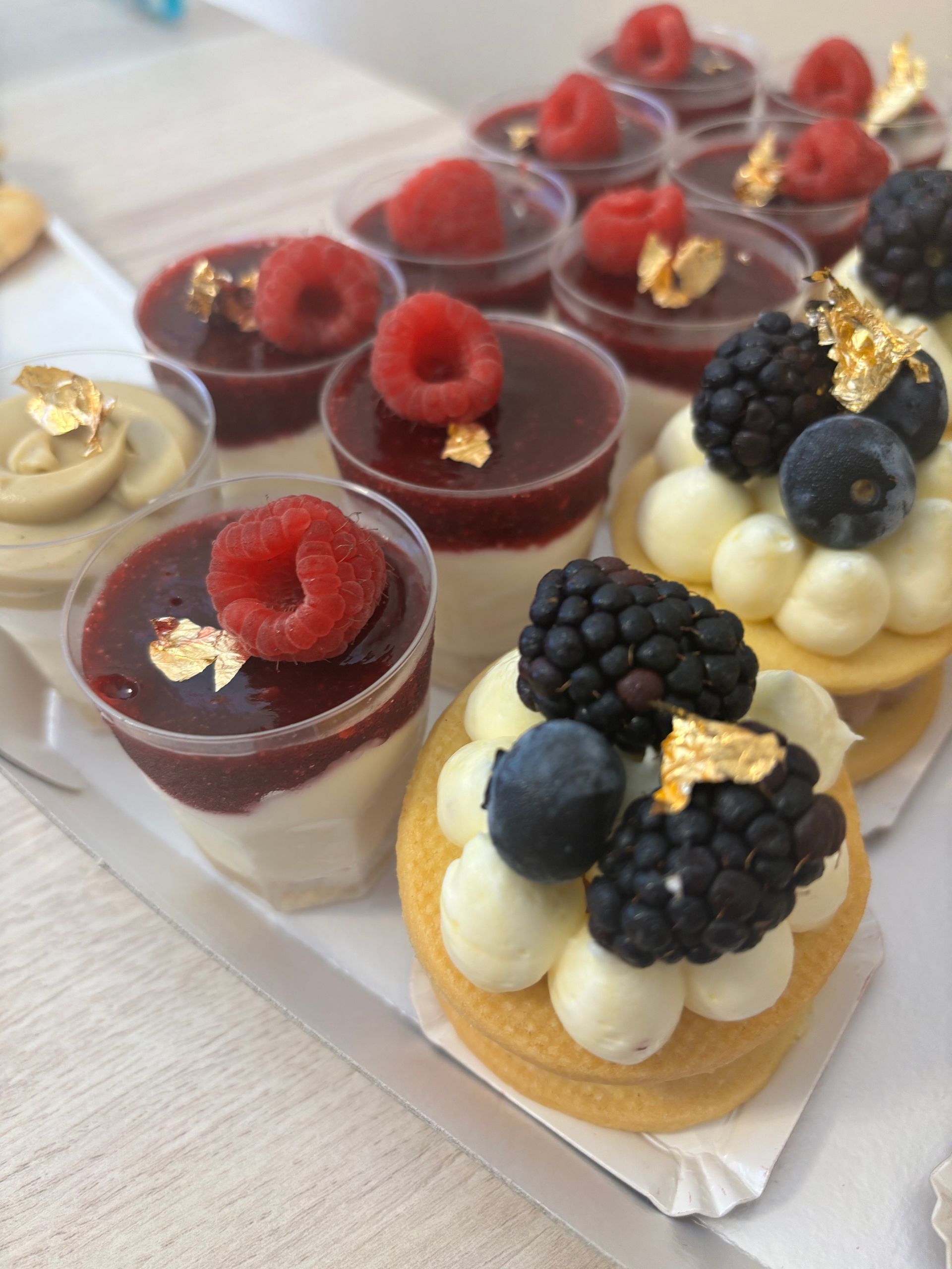 Pasticcini esposti in una vetrina di vetro, tra cui cupcake con lamponi e cioccolato e panini zuccherati.