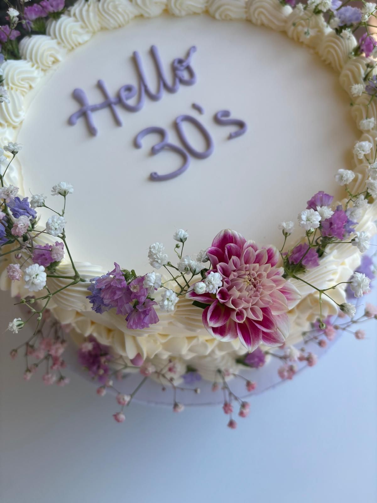 Torta mousse a tre strati con strati bianchi, al cioccolato e marroni, guarnita con more, su un'alzata in legno.