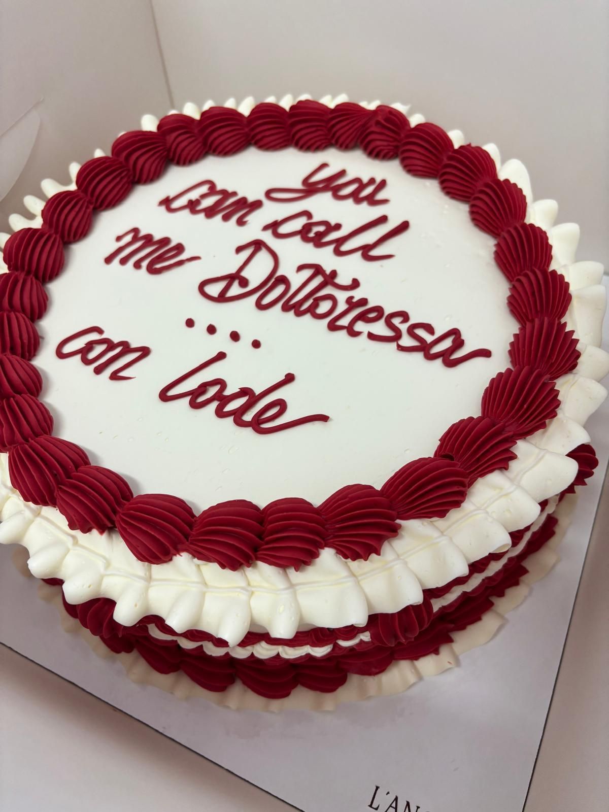 Dessert su piatto bianco: pasta sfoglia rotonda color nocciola su una base marrone, con pezzetti di mandorle sparsi.