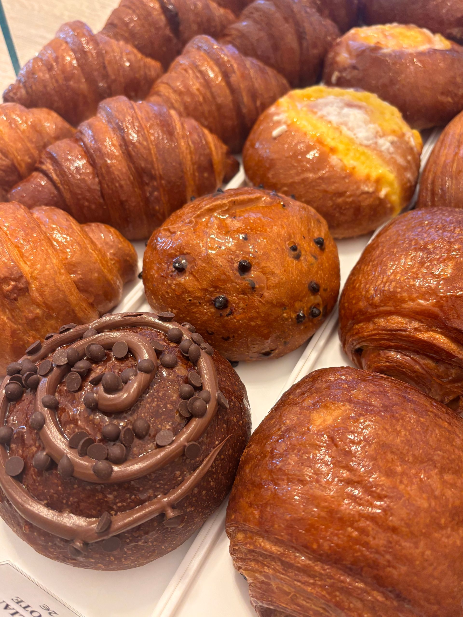 Dolce al cioccolato su oro, tazza da caffè, vecchi libri, cucchiai di legno e noci sparse su una superficie bianca.