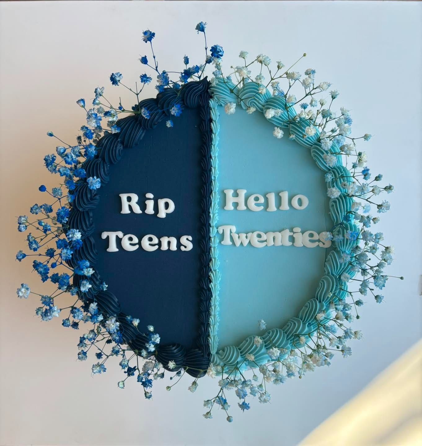 Torta decorata con le scritte "Rip Teens" e "Hello Twenties" in bianco, metà blu, metà azzurro e gypsophila.