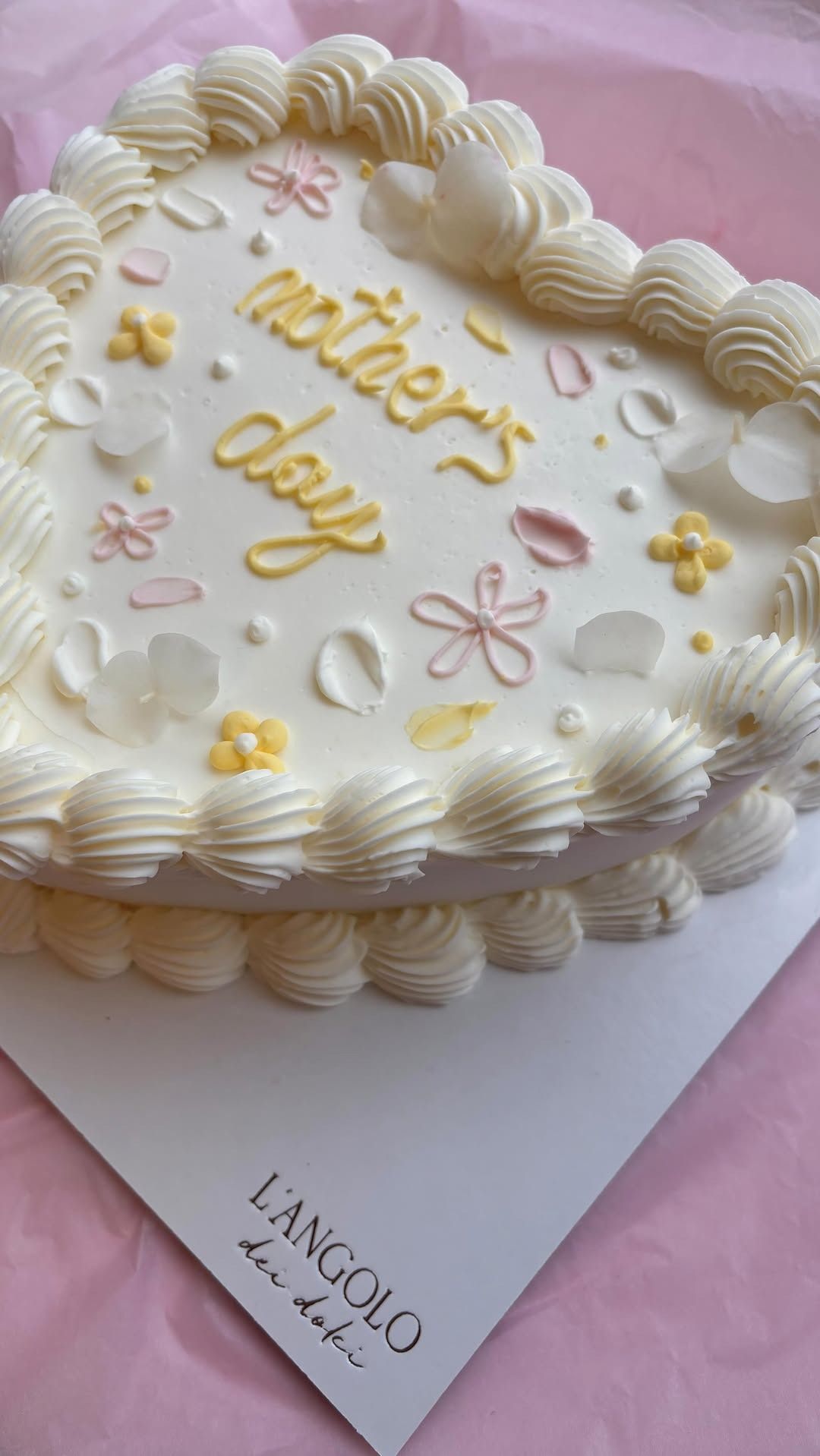 Torta per la festa della mamma a forma di cuore con glassa alla crema, fiori pastello e scritta 