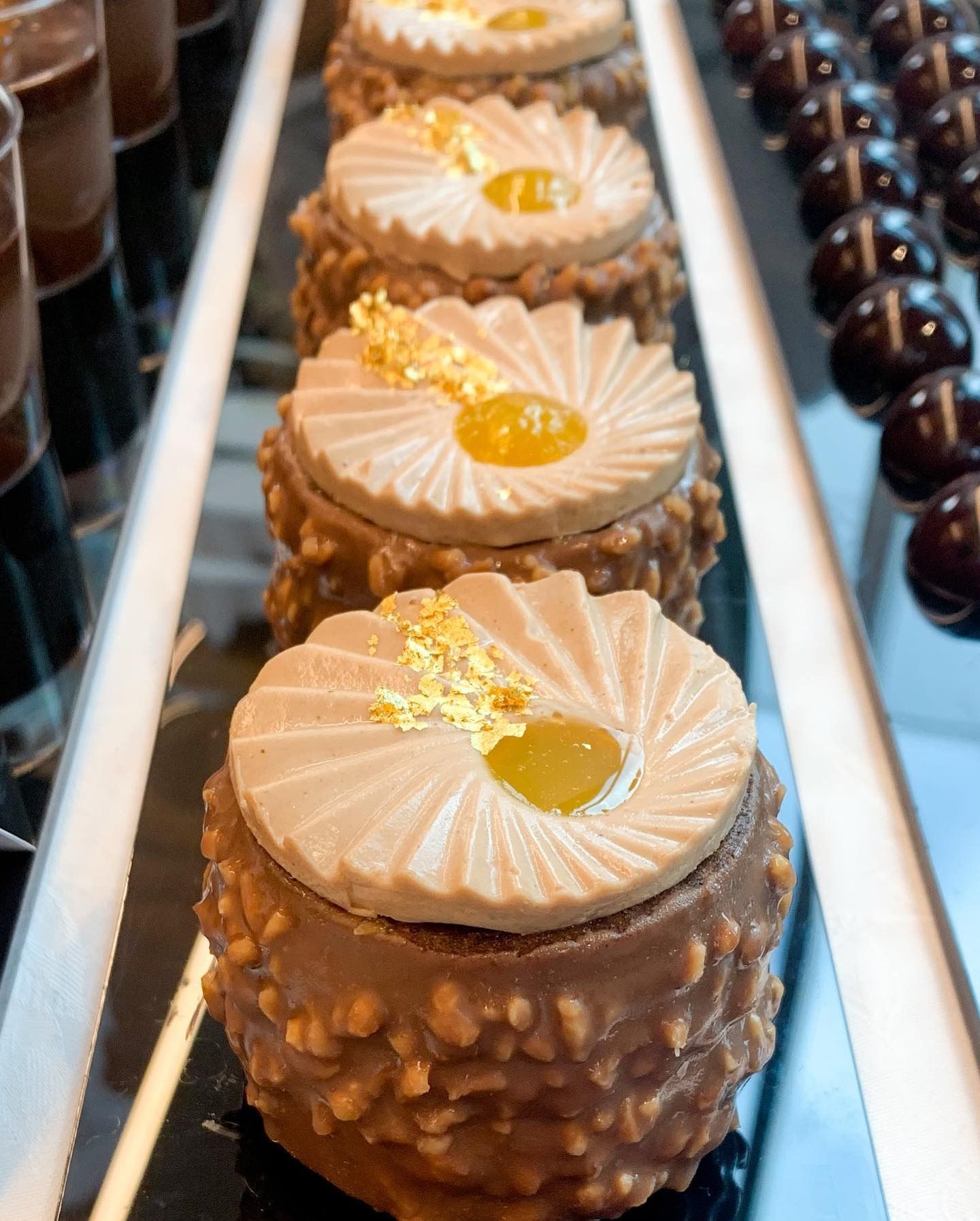 Caffè in una tazza con bordo dorato, fette di limone, dessert e cucchiaio su un tagliere di legno con spighe di grano.