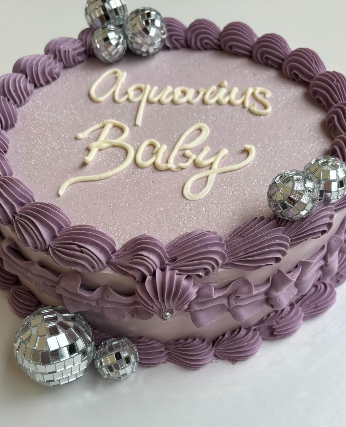 Torta alla lavanda con decorazioni a forma di palla da discoteca e scritta 