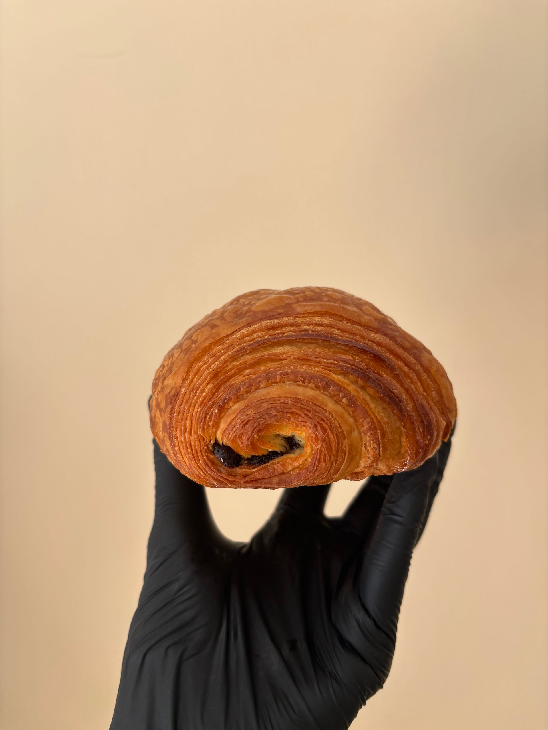 Pasticcini esposti in una vetrina di vetro, tra cui cupcake con lamponi e cioccolato e panini zuccherati.