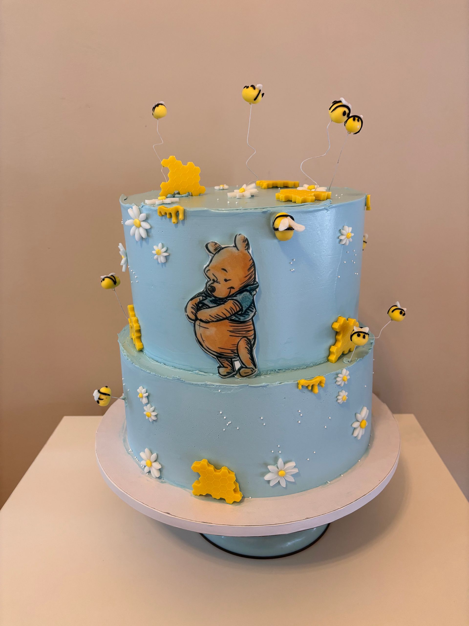 Torta a due piani a tema cowgirl con motivi rosa e in pelle di mucca, decorata con un cappello, stivali e uno striscione.