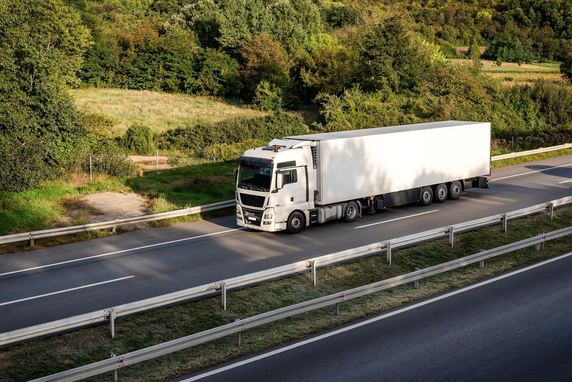 A white semi truck is driving down a highway.