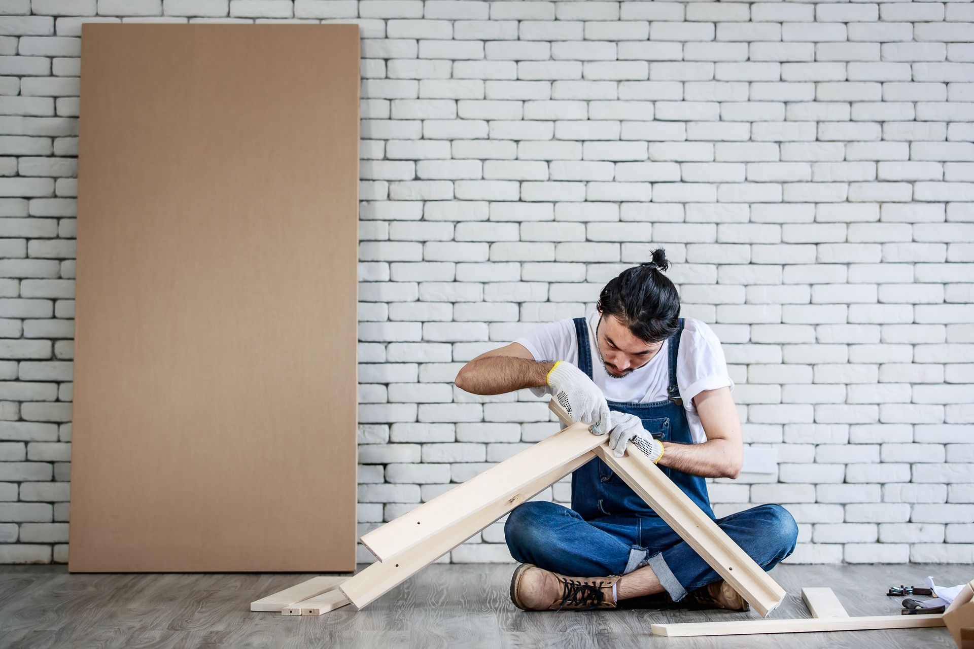 A man is sitting on the floor working on a piece of wood.