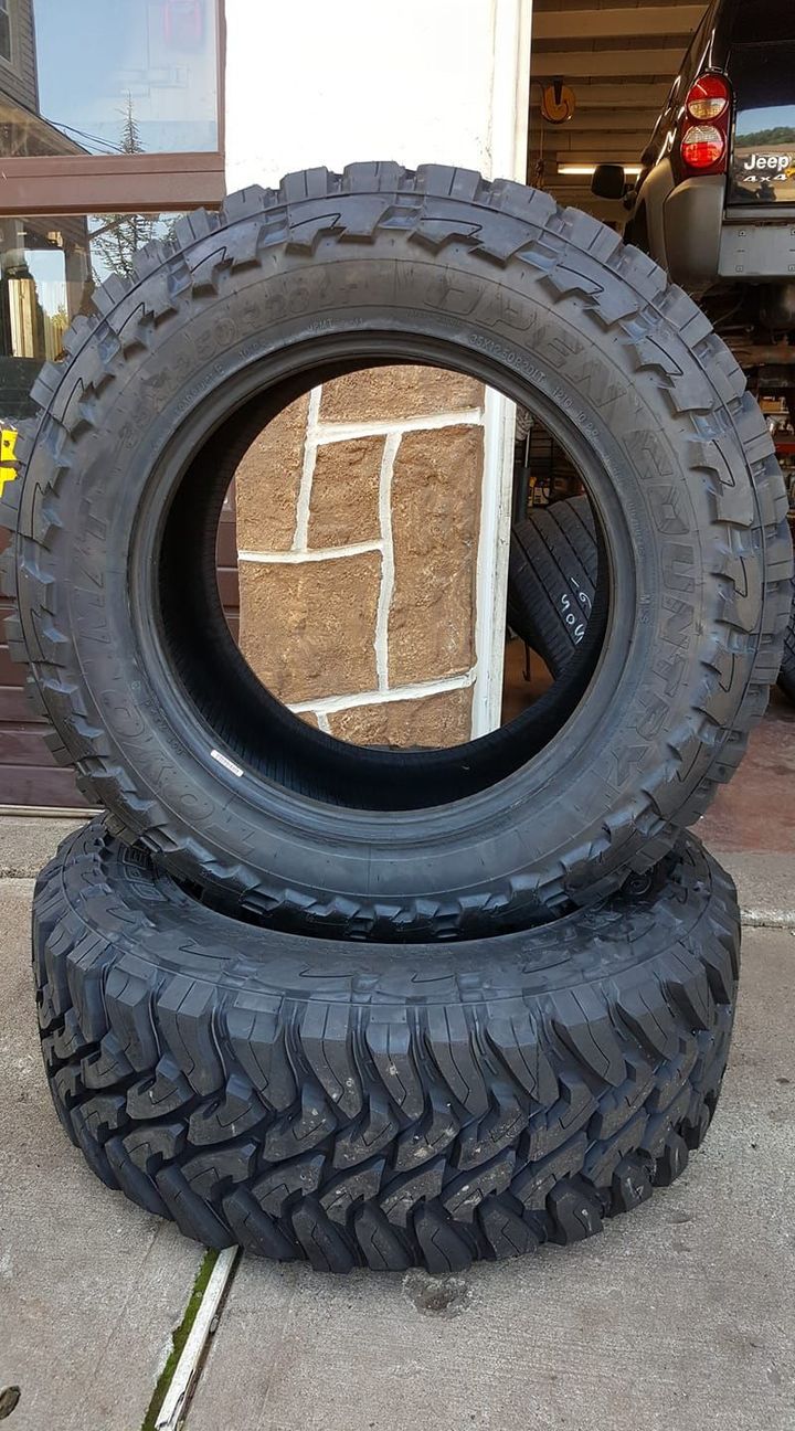 Two tires are stacked on top of each other on the sidewalk.