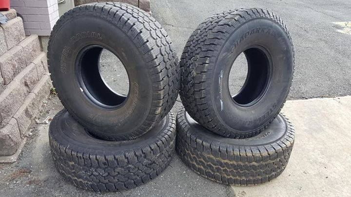 Four tires are stacked on top of each other on the sidewalk.