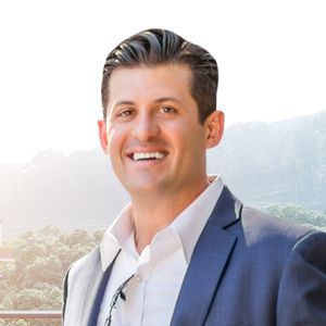 Joe in a suit and white shirt is smiling for the camera.