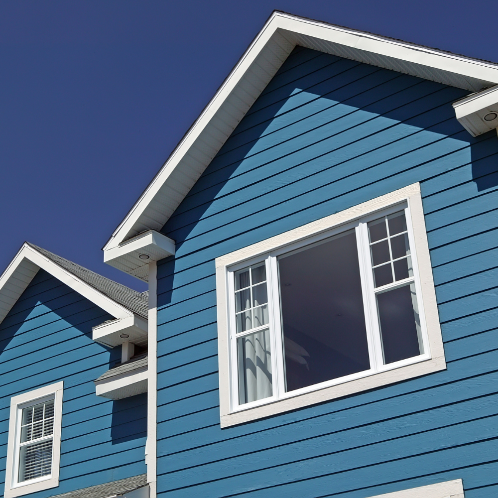 Blue house with white trim and windows against a clear blue sky.