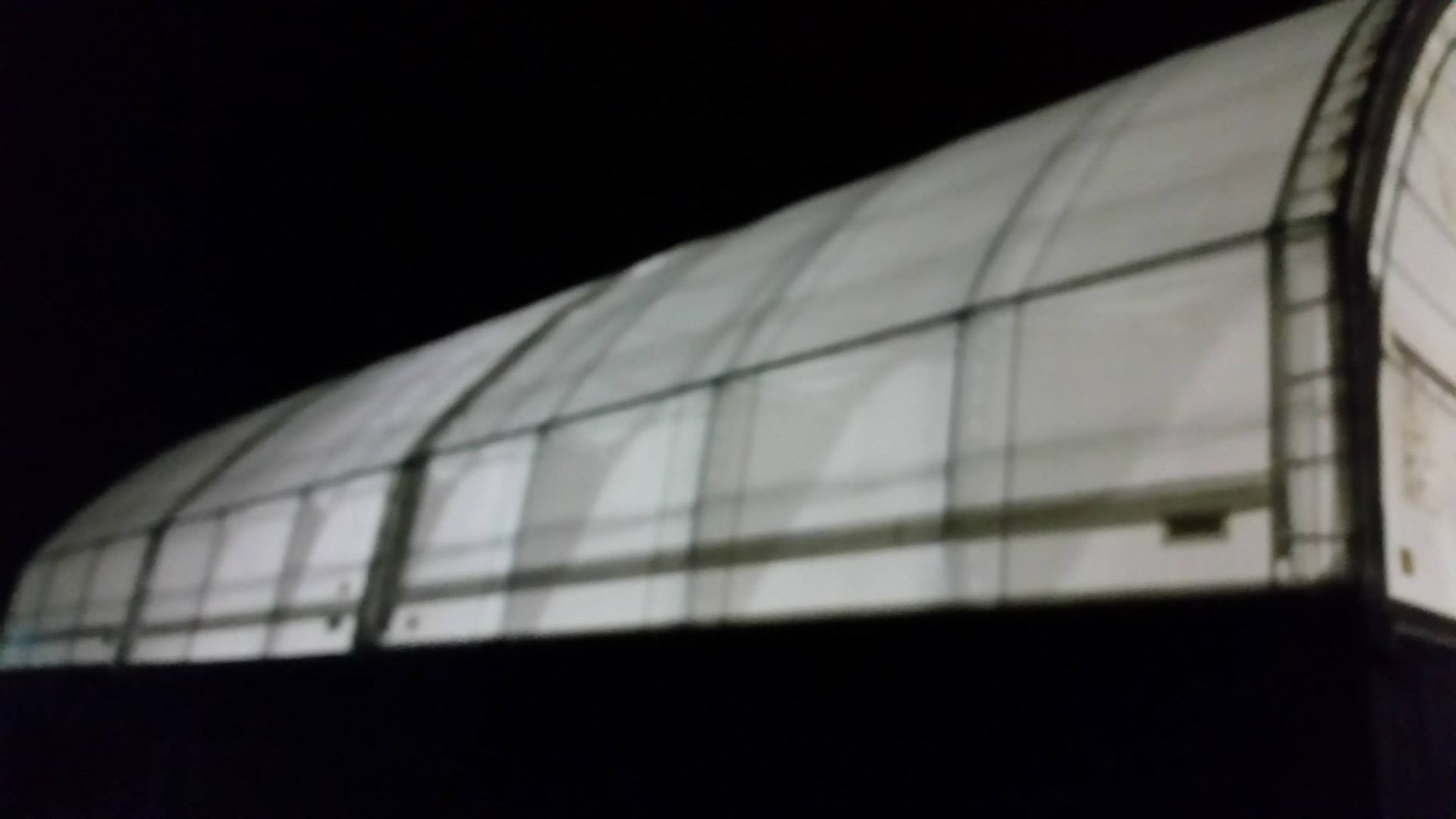 White arched roof structure, likely for storage or shelter, against a dark sky.