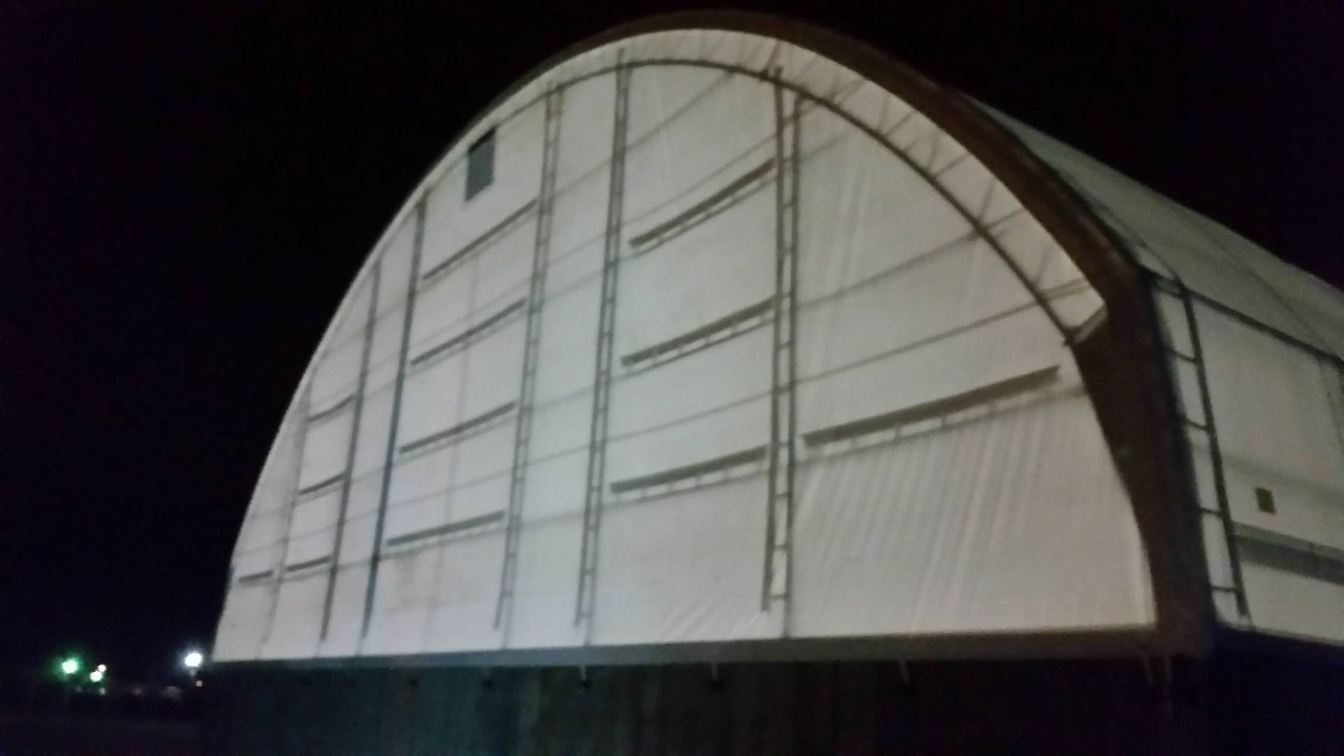 Arched white building with metal frame at night.