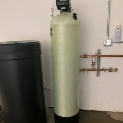 A water filter is sitting next to a black tank in a room.